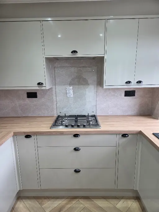 Fitted kitchen with wood worktop and glass splashback